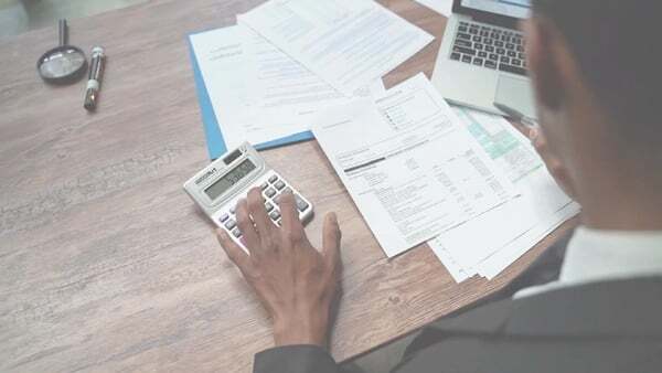 Video thumbnail showing an overhead shot of a man with a calculator and paperwork on his desk