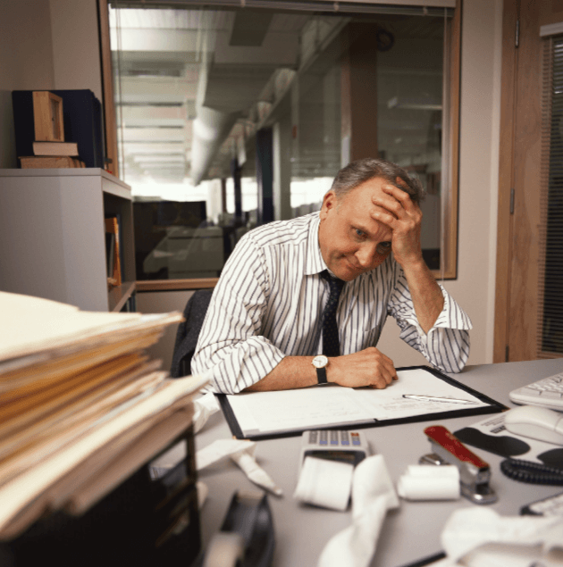 Frustrated man at desk with left hand on head
